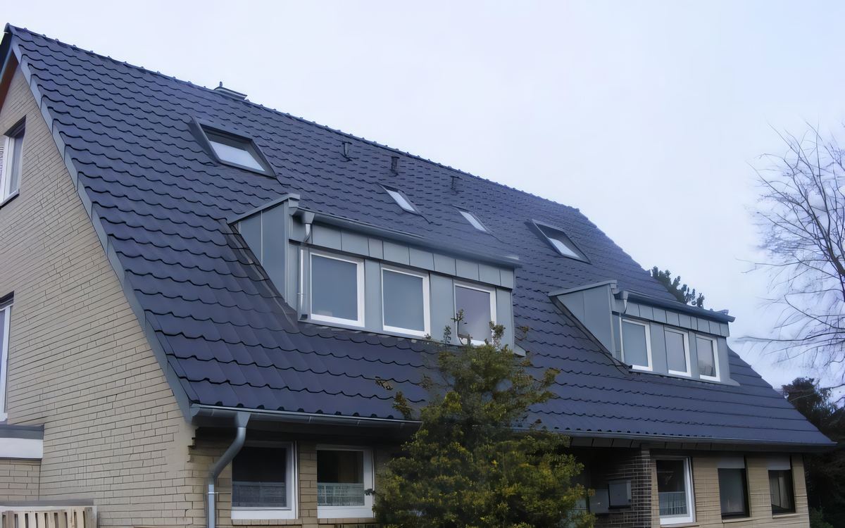 Nachher: dasselbe Haus mit anthrazitfarbener Eindeckung, metallbekleideten Gauben und Dachfenstern