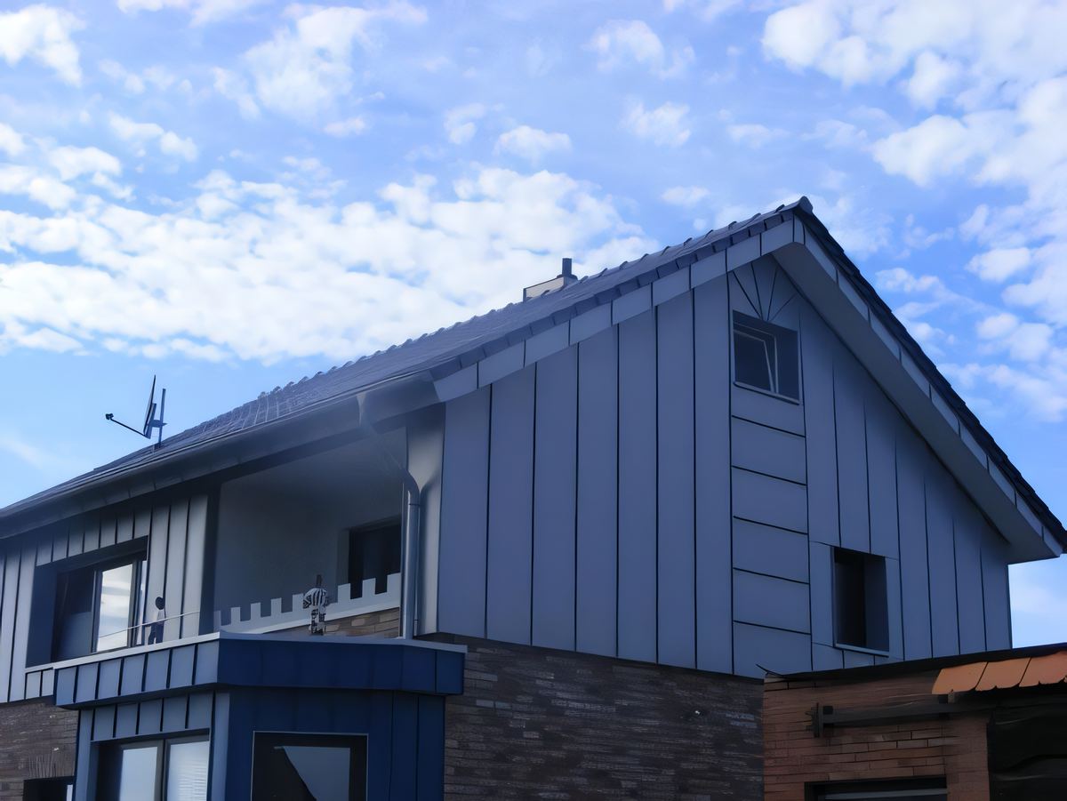 Einfamilienhaus mit blaugrauer Stehfalzbekleidung am Giebel und blau bekleidetem Erker im Erdgeschoss