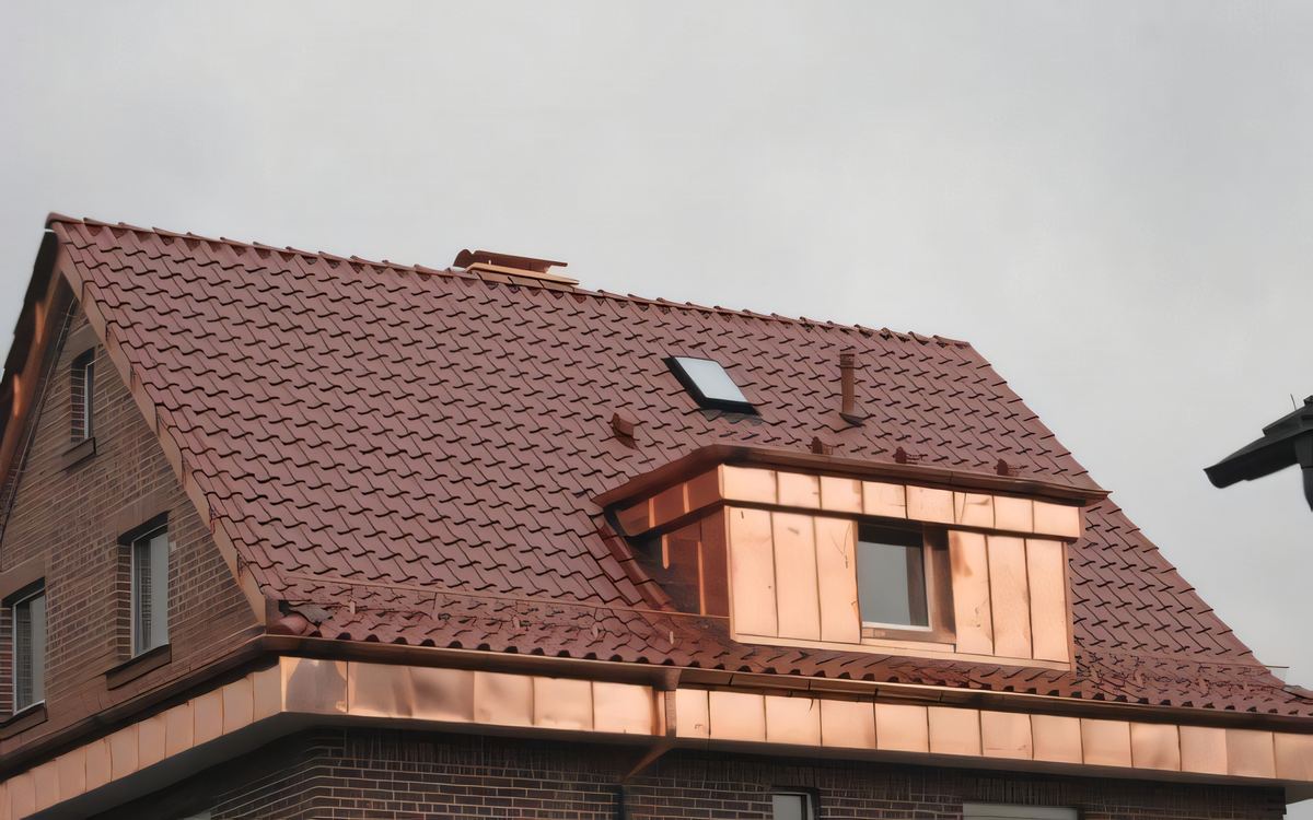 Kupfergaube mit Kupfertraufe auf dem roten Ziegeldach eines Klinkerhauses