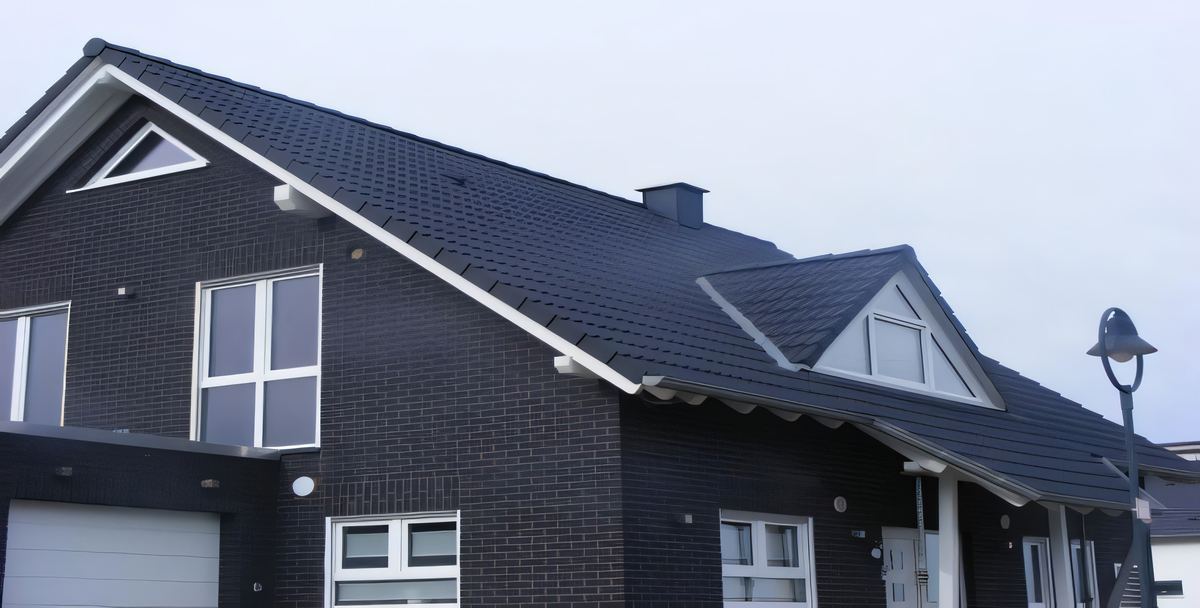 Dunkles Klinkerhaus mit anthrazitfarbenem Dach und weiß bekleideten Giebeldreiecken