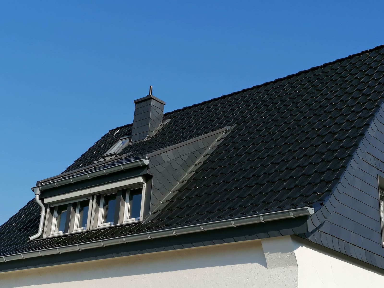 Gaube mit Metallabdeckung und seitlicher Schieferbekleidung auf einem dunklen Ziegeldach